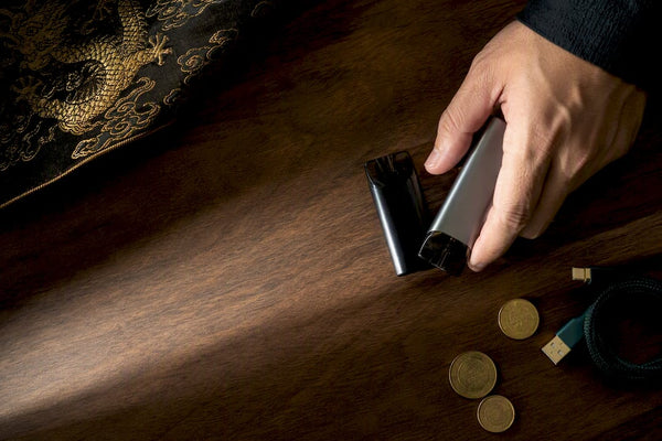 Anonymous vape devices beside coins and charger